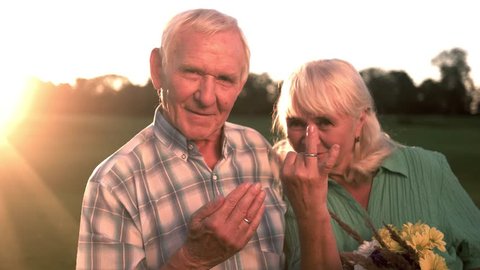 Smiling elderly couple with bouquet. Two hands with rings 