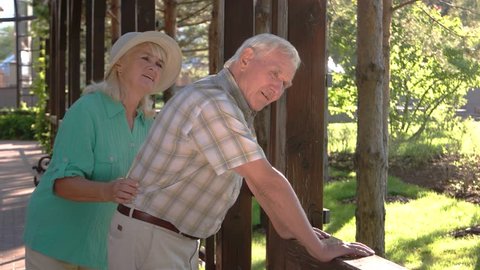 Old man has backache. Elderly couple outdoors. 