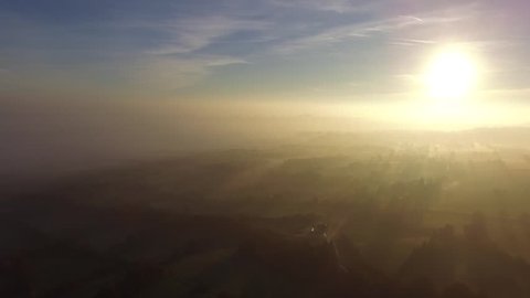 Aerial view looking over foggy fields at sunrise.