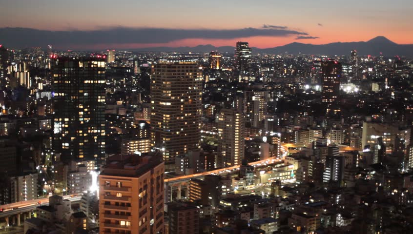 Sun setting over Tokyo, Japan with cars rushing over high-ways and Mt. Fuji in the background