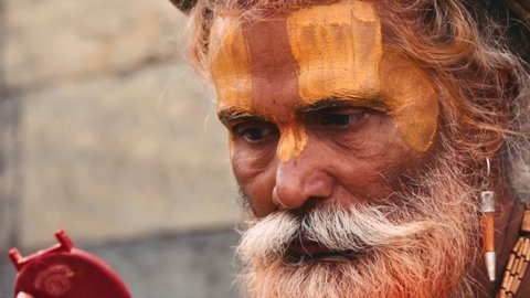 Sadhu painting himself with traditional make up. Closeup. Kathmandu Nepal