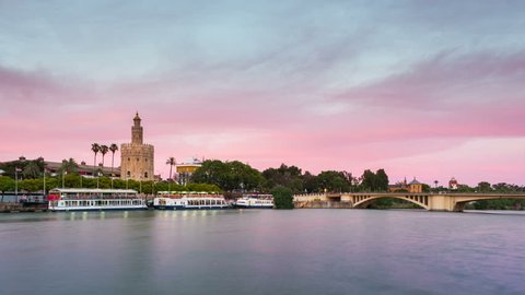 View of Golden Tower, Torre del Oro, of Seville, Andalusia, Spain over river Guadalquivir at sunset. Sunset timelapse with transition from day to night.
