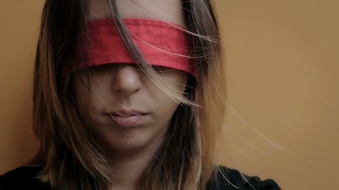 abused woman with eyes blindfolded with red ribbon