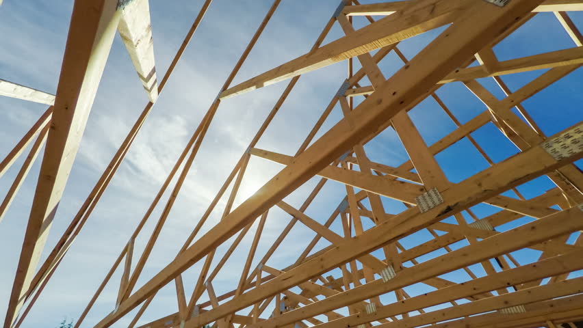 Roof beams of a modern American home in mid construction phase, looking up toward blue sky with sunlight Royalty-Free Stock Footage #20181772
