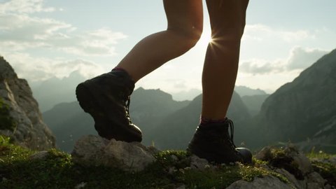 SLOW MOTION, CLOSE UP: Unrecognizable courageous female hiker climbing mountaintop, walking off trail on dangerous rocky mountain ridge. Steep wall opening beautiful view on high European Alps
