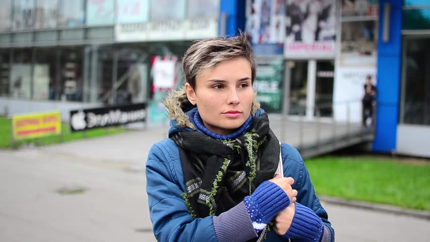 Woman standing on the street and waiting for someone. She is turning around.