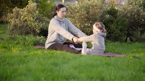 Sporty mother and daughter training in the park at the evening