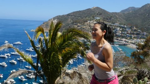 Attractive Asian woman jogging. The bay and town of Avalon on Catalina Island are in the background.