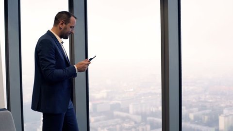Young businessman standing with tablet by window in the office
