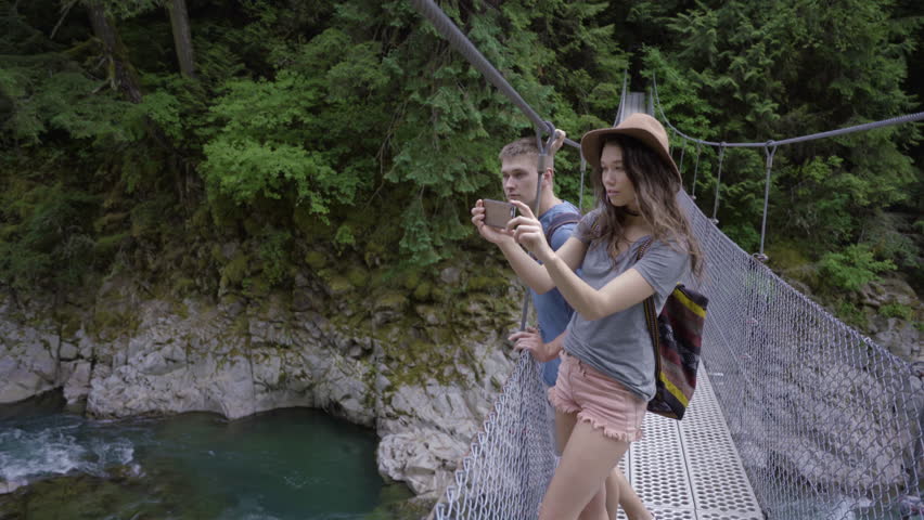 Hikers Stop On Suspension Bridge To Take Photos With A Smart Phone