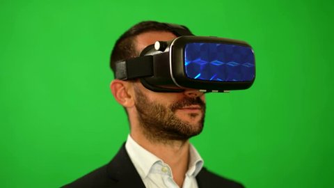 Man in suit uses virtual reality goggles. VR. Green background. The man is in virtual reality. High-tech devices. The movement of the head on a green background. Virtual reality helmet. 4K resolution. Arkistovideo