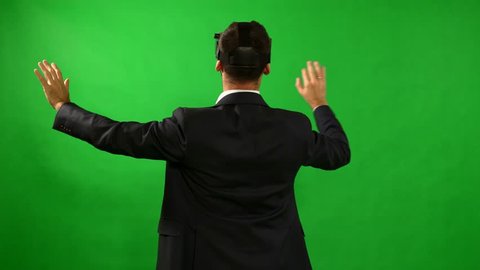 Man in suit uses virtual reality goggles. VR. Green background. A man uses virtual interface. High-tech devices. The movement of the hands on a green background. Virtual reality helmet. 4K resolution. स्टॉक वीडियो