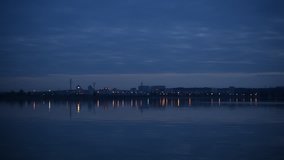 Urban landscape with city lights reflected in water in the evening with many transmission towers. Shot in Ukraine on Dnieper river near Kiev