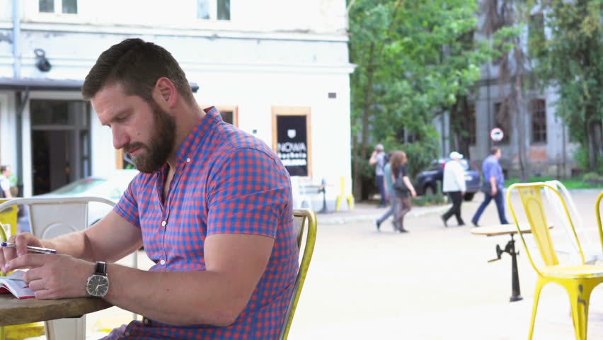 Young man reading book in cafe, slider shot left