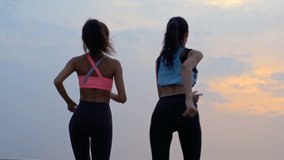 Back view of two beautiful young sports women jogging on beach