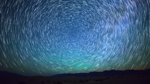 Astrophotography time lapse with pan left motion of star trails over sand dunes in Death Valley National Park, California