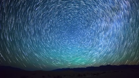 Astrophotography time lapse with pan right motion of star trails over sand dunes in Death Valley National Park, California