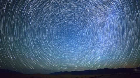 Astrophotography time lapse with zoom out motion of star trails over sand dunes in Death Valley National Park, California