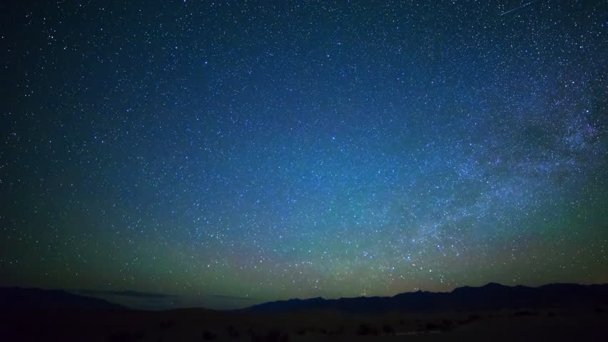 Astrophotography time lapse with pan right motion of stars orbiting around North Star over sand dunes in Death Valley National Park, California