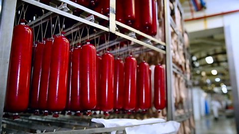 Meat Product Manufacturing. Storage Room. Sausages in Red Plastic Packaging Handing on the Metal Shelves. Closeup