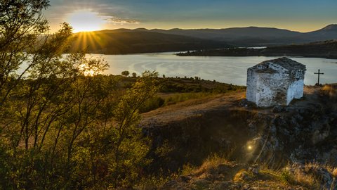 4K Tracking, panning and tilting day to night timelapse of a church on hilltop over a big dam surrounded by mountains.