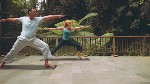 Balinese yoga teacher and caucasian woman doing warrior pose and extended side angle pose