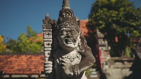 Balinese man stone statue in front of balinese gates and fountain, slide