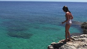 Girl jumping into the sea from the high rock. Medium Shot, Handheld Shot, Slow motion, contains girl 10-12 years. Montenegro, Adreatic sea.