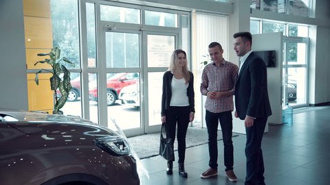 Couple comes into Car dealership to choose the car to buy it. The sales manager approaches them and begins to tell about petrol and electric vehicles
