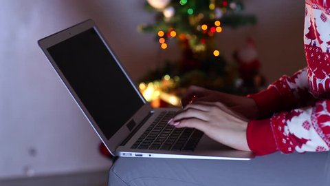 Girl Woman Hand Presses Keyboard and Touchpad Laptop Uses New Technology on Eve Christmas, New Year 2017. Against Tree and Bokeh Colorful Lights. the Concept of Using Devices, Business, Holidays.