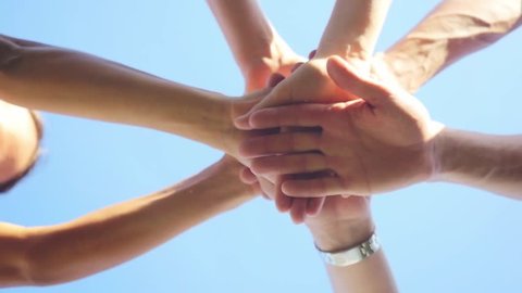 Successful team: many hands holding together on sky background in slowmotion. 1920x1080