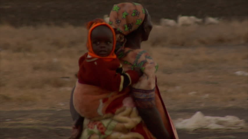 Kenya - Circa 2006: Unidentified woman walks while carrying a child on her back