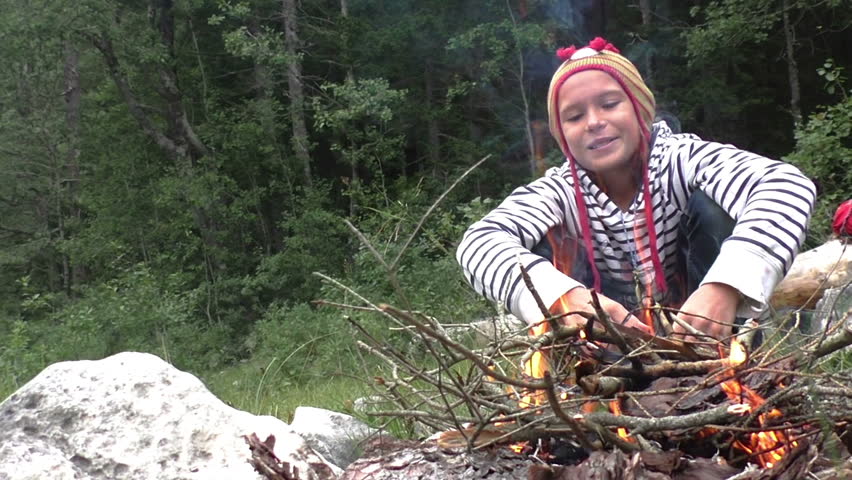 Girl is sitting near the fire in hike. Medium Shot, Handheld Shot, Slow motion, contains teen girl 10-12 years. Montenegro, Durmitor mountains.