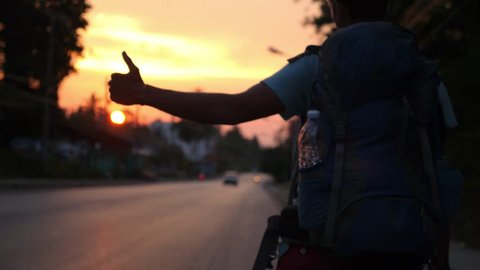 Traveller with Backpack Hitchhiking on Road Travel at Sunset