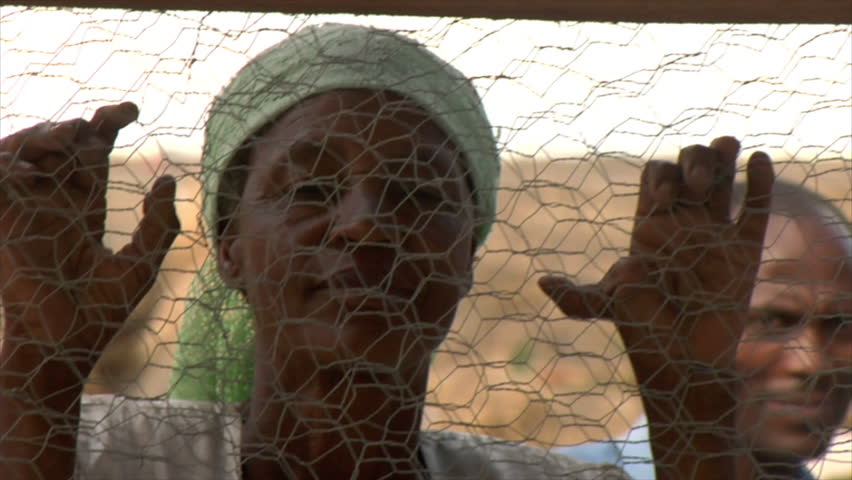 KENYA - CIRCA 2006: Unidentified people look through a fence at chickens circa