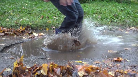 Boy jumping in muddy puddle, slow motion 250 fps