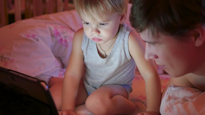 the little child with the father watching cartoons on a tablet in the evening
