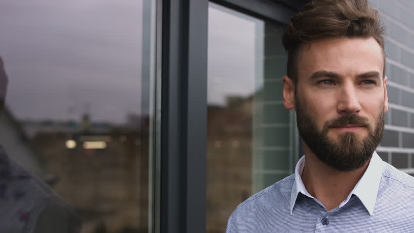 Successsful worker looking at the window and finishing his coffee.