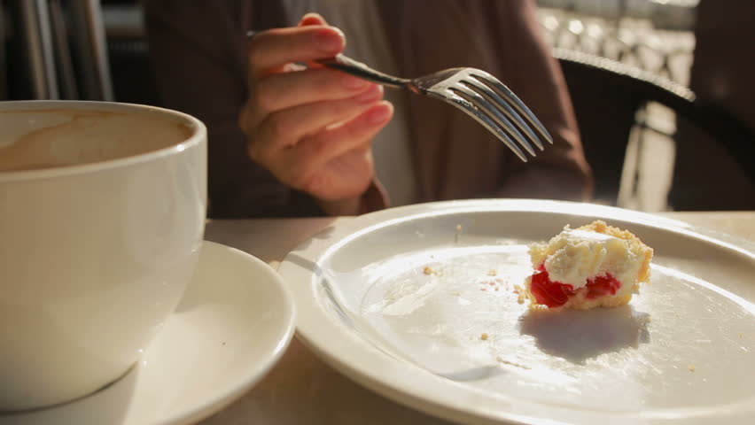 woman eating cake at outdoors cafe. cheese cake closeup