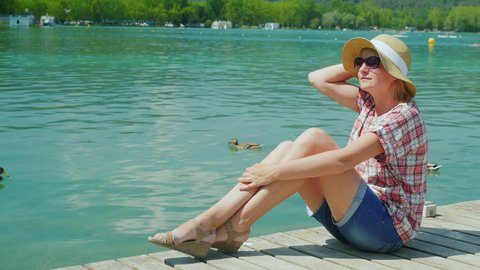 A woman tourist enjoying vacation at the lake where ducks swim. Resort in Spain