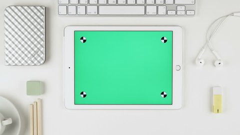 Moscow, Russia - October, 03, 2016: A man sliding green chroma key pictures on Apple iPad Air display at his desk. iPad is an iOS based line of tablet computers designed and marketed by Apple Inc