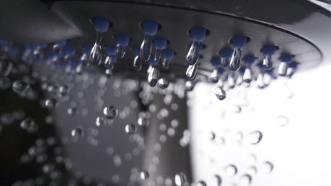 Shower head in bathroom with water drops flowing. Slow motion
