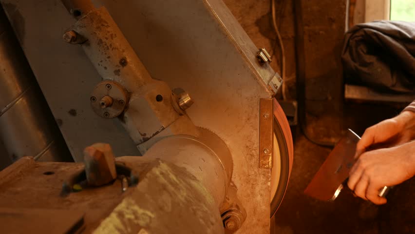 The blacksmith sharpening an ax on electrical grinder