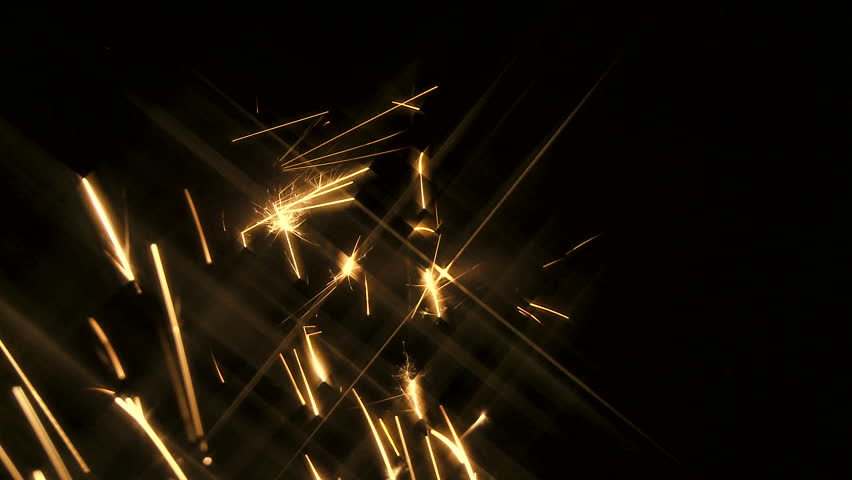 Gold sparks with star flare shoot up into frame