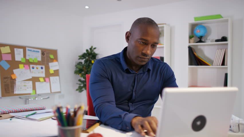 4K Businessman working at his desk in office, working on computer & talking on phone. Shot on RED Epic.