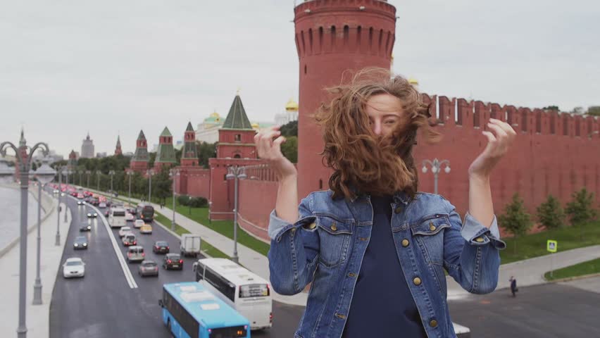 Tourist on travel smiling and hair fluttering in the wind in fron of famous Russian tourist destination and attraction in Moscow. Woman traveler on vacation.
