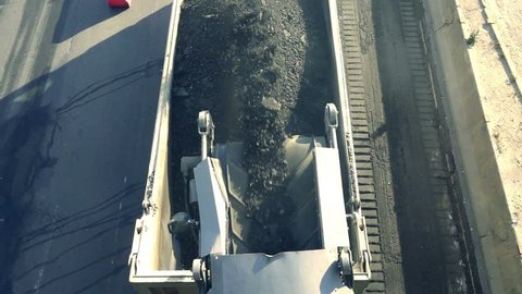 Cold milling machine, milled asphalt falls into the back of the truck, top view, slow motion
