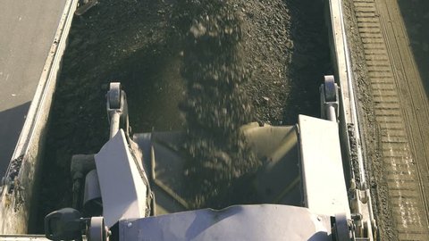 Cold milling machine, milled asphalt falls into the back of the truck, close up, top view