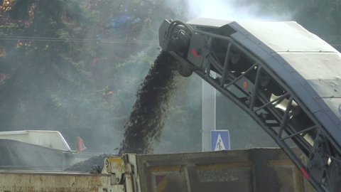 Cold milling machine, milled asphalt goes the conveyor belt to the truck, slow motion