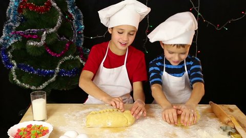 Two kids kneading the dough for christmas cookies
